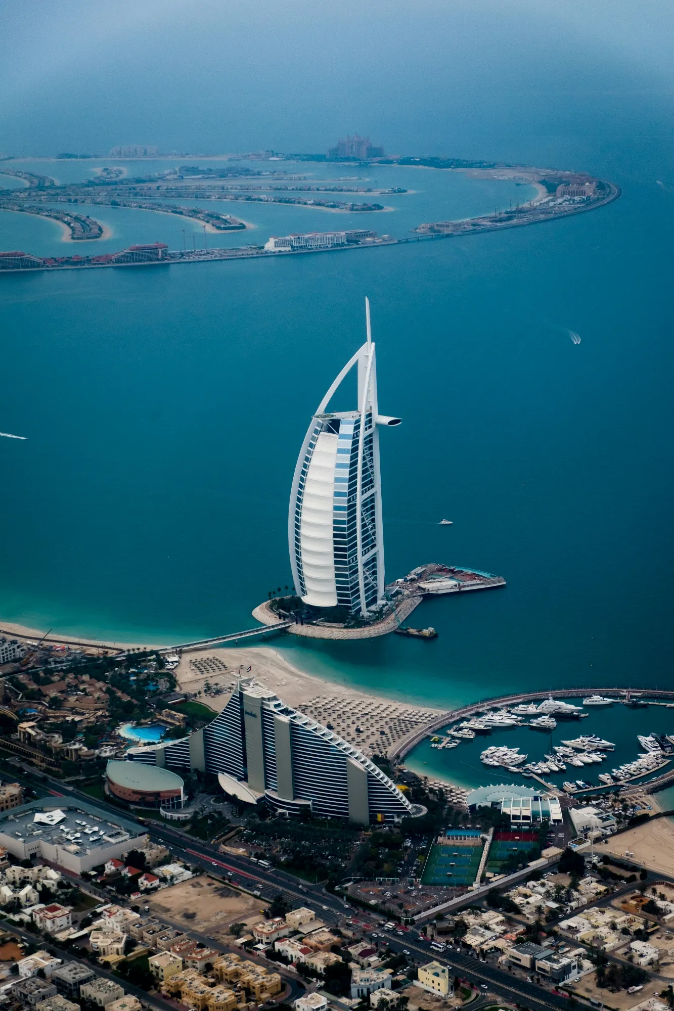 Aerial view of the Burj Al Arab and Dubai coastline representing real estate law advisory services by THINC Dubai.