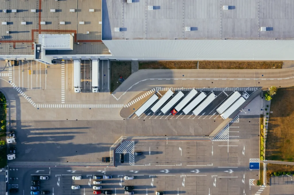 Aerial view of logistics trucks and warehouse operations representing shipping and compliance advisory by THINC Dubai.