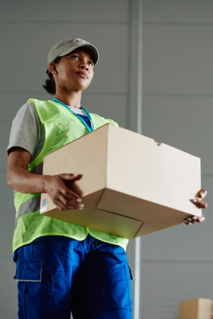 A logistics worker carrying a delivery box, reflecting e commerce operations, cross border compliance, and supply chain regulations in the UAE and GCC.