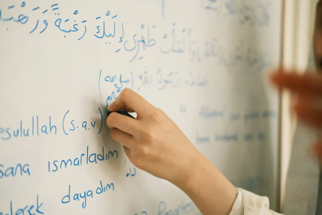Close up of a teacher writing Arabic text on a classroom whiteboard, representing education, teaching, and academic instruction in the region.